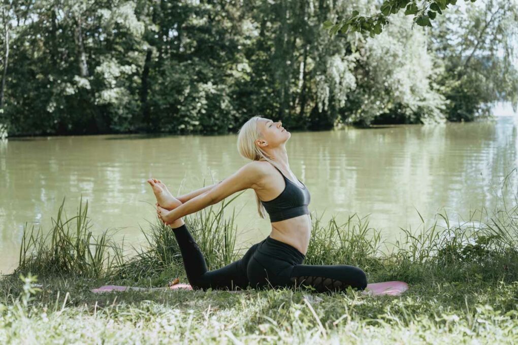 Frau macht Yoga im Freien am See