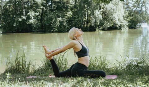 Frau macht Yoga im Freien am See