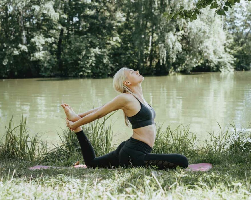 Frau macht Yoga im Freien am See