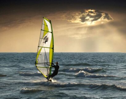 Windsurfer fährt auf dem Wasser Richtung Sonnenuntergang