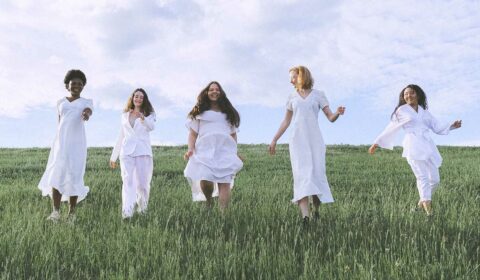 Frauen laufen gemeinsam mit weißen Klamotten über eine Wiese