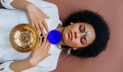 Frau liegt auf dem Rücken und macht eine Halschakra Meditation