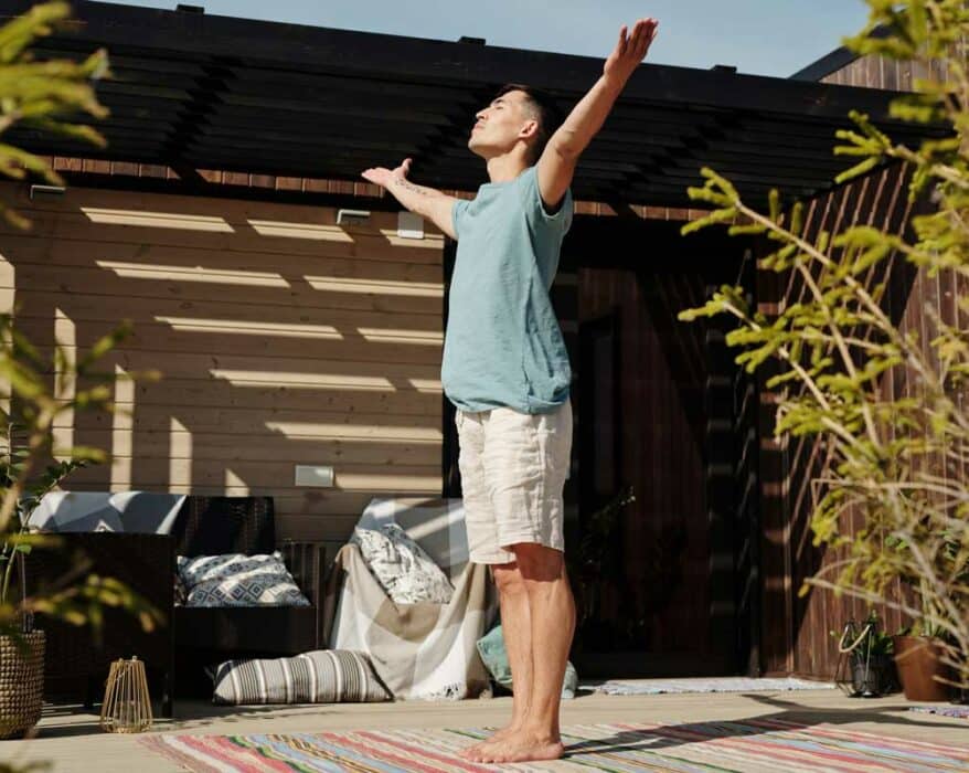 Mann macht Sonnengrüße draußen auf der Terrasse