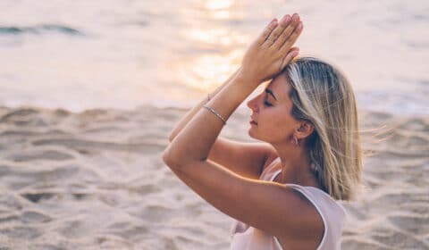 Frau macht Yoga am Meer