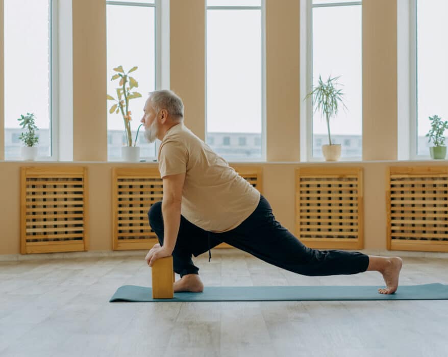 Senior macht Yoga mit seiner Krankheit Arthritis