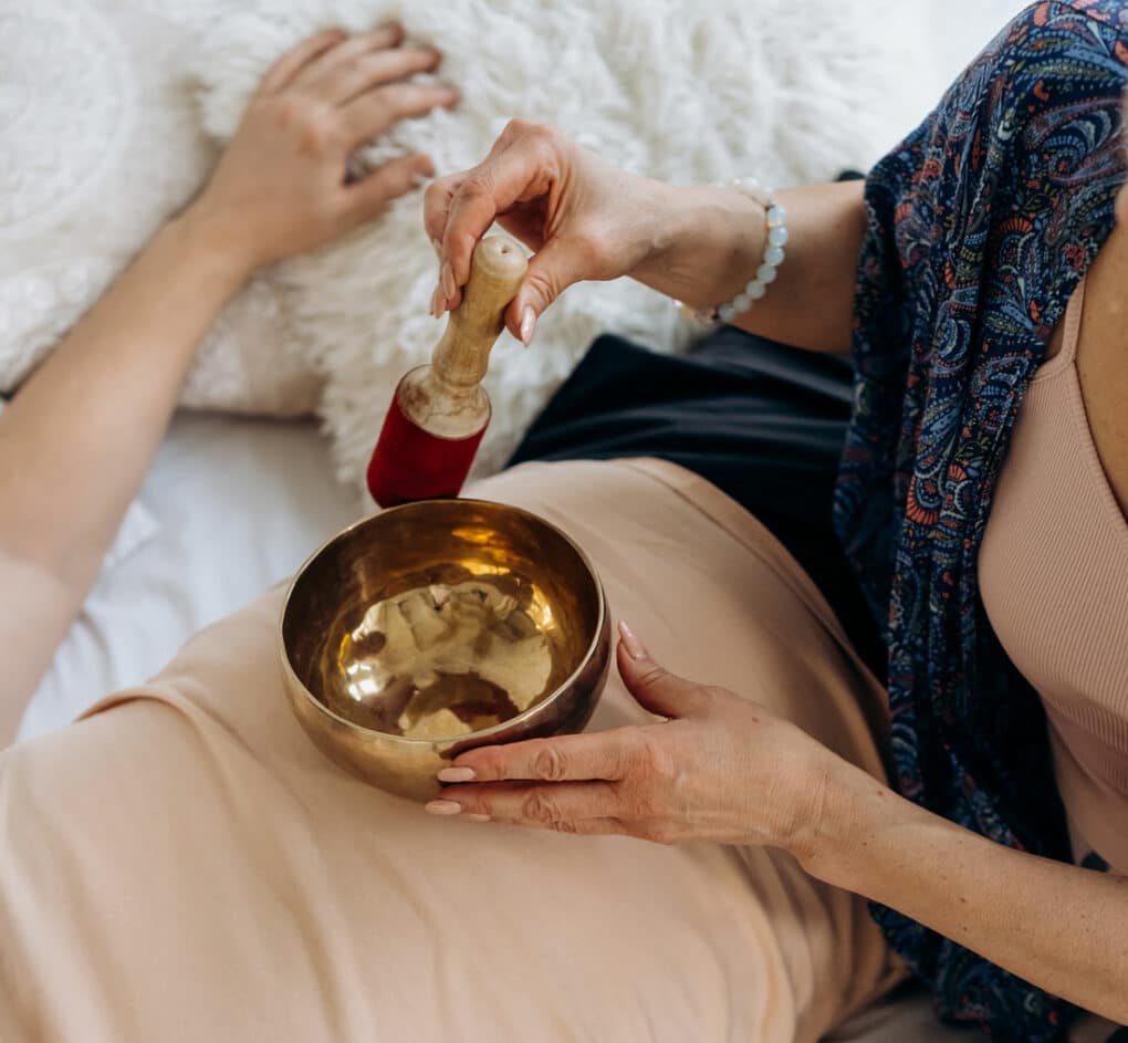 Frau macht eine Klangschalenmeditation auf dem Bauch einer Frau
