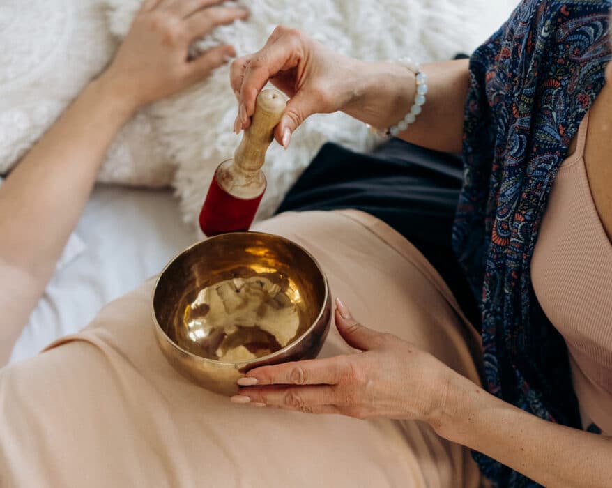 Frau macht eine Klangschalenmeditation auf dem Bauch einer Frau