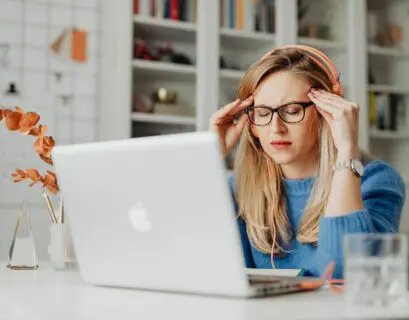 Frau sitzt gestresst vor ihrem Mac Laptop