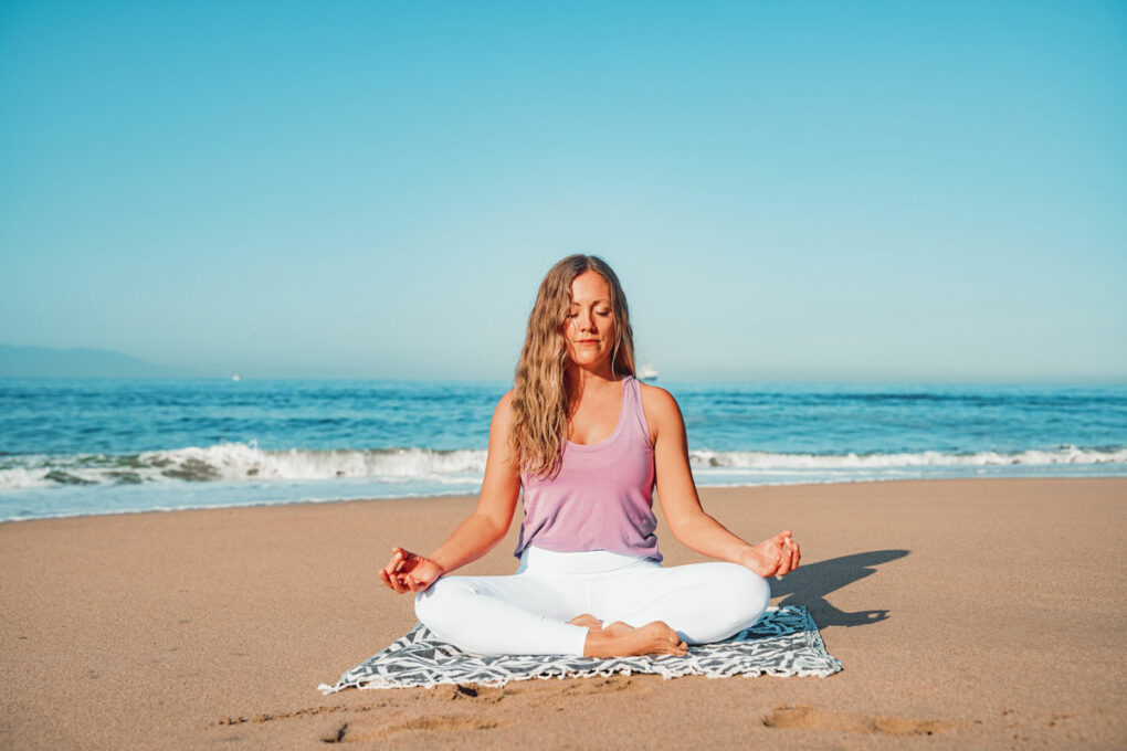 Frau macht Yoga am Strand von Dänemark