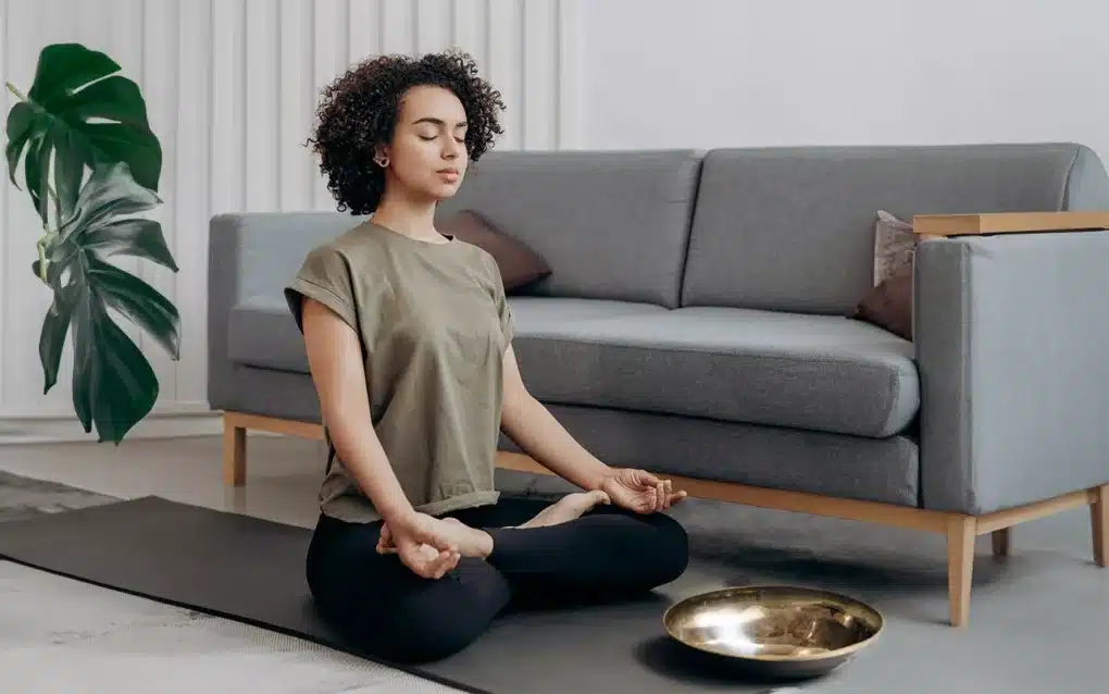Frau sitzt auf dem Boden und macht Meditation bei Migräne