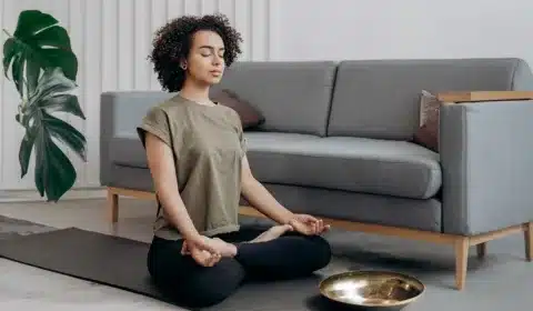 Frau sitzt auf dem Boden und macht Meditation bei Migräne
