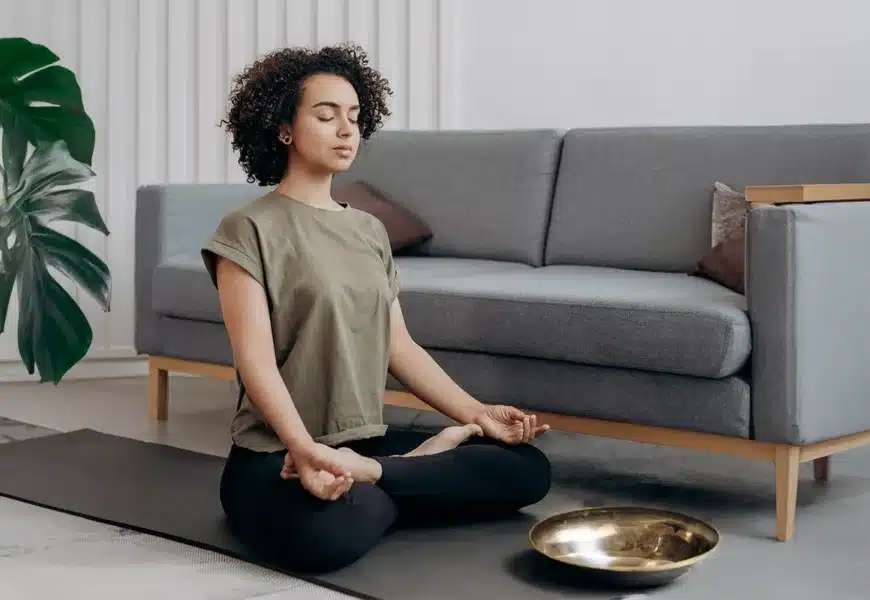 Frau sitzt auf dem Boden und macht Meditation bei Migräne