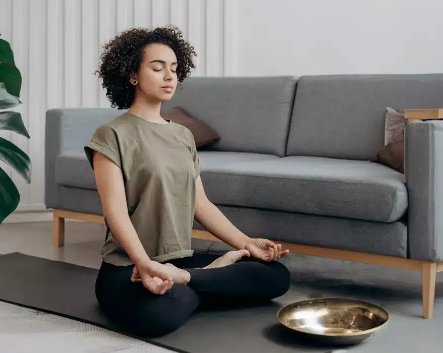 Frau sitzt auf dem Boden und macht Meditation bei Migräne