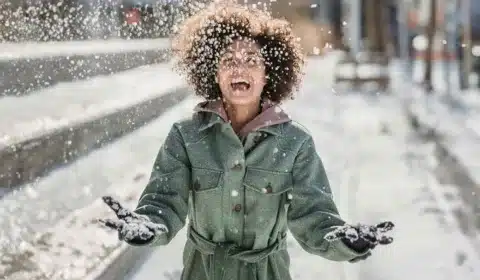 Frau ist draußen und wirft glücklich Schnee in die Luft