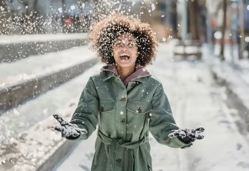 Frau ist draußen und wirft glücklich Schnee in die Luft