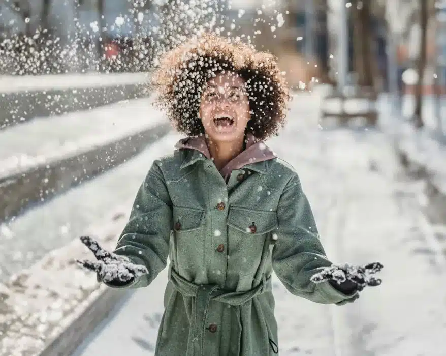 Frau ist draußen und wirft glücklich Schnee in die Luft