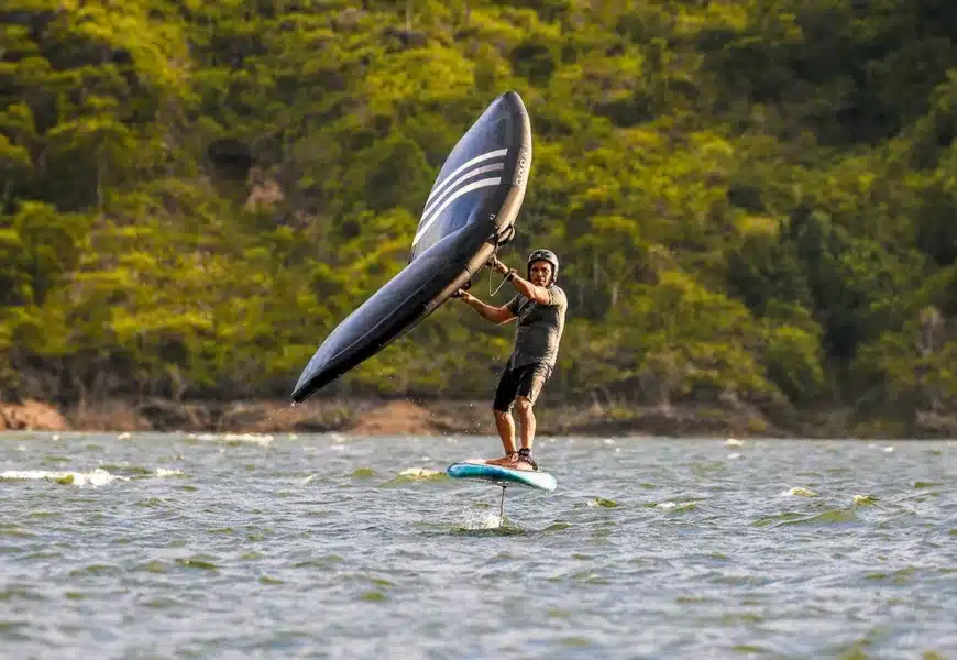 Mann foilt mit seinem schwarzen Wing auf dem See nachdem er Yoga gemacht hat