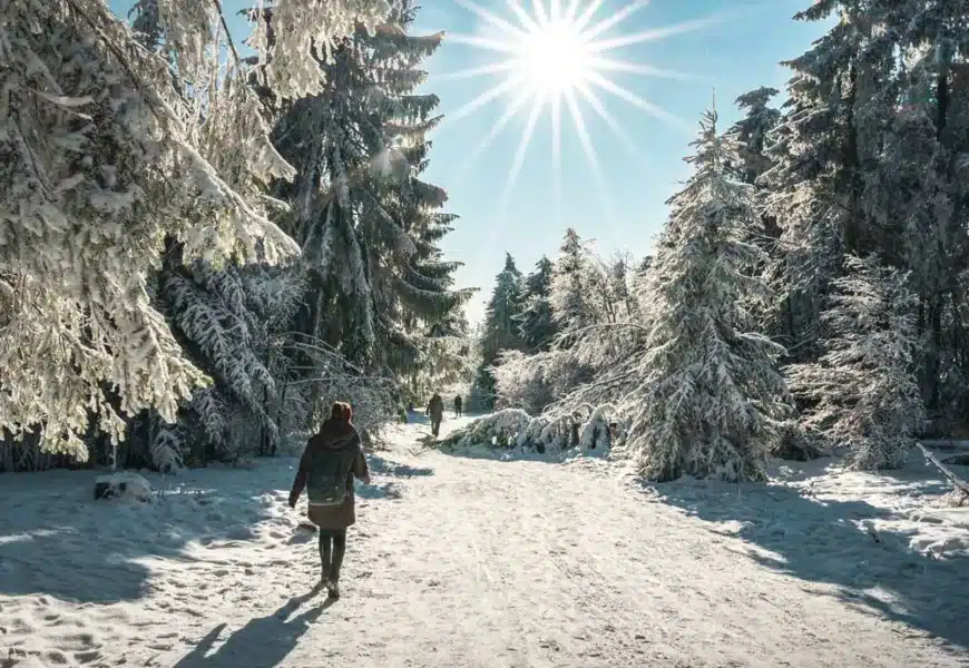 Frau läuft durch das sonnige und zugeschneite Winterwonderland