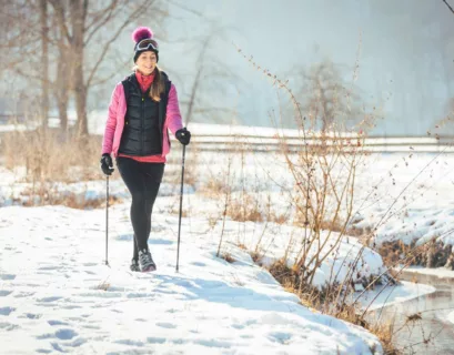 Frau macht im Schnee eine Winterwanderung mit Walking Stöcken