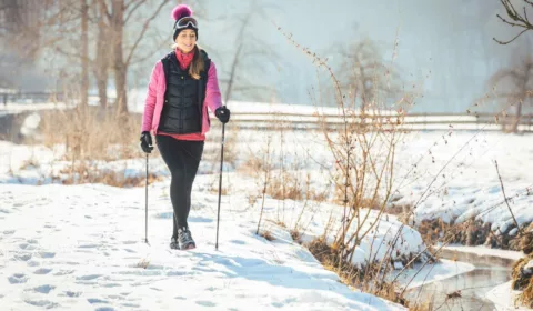 Frau macht im Schnee eine Winterwanderung mit Walking Stöcken