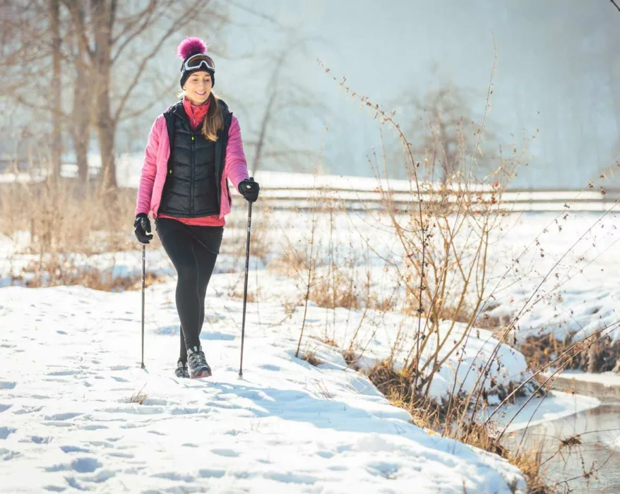 Frau macht im Schnee eine Winterwanderung mit Walking Stöcken