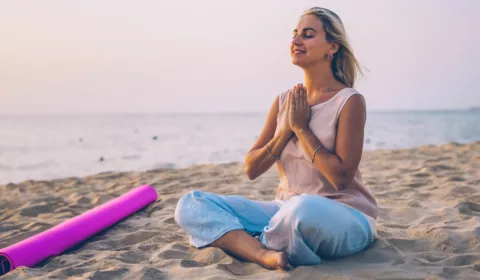 Frau macht Yoga am Strand