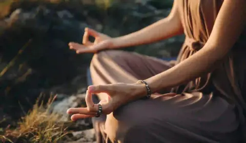 Frau meditiert im Meditationssitz und hält ein Finger Mudra