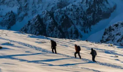 drei personen mache eine Wanderung durch den schnee