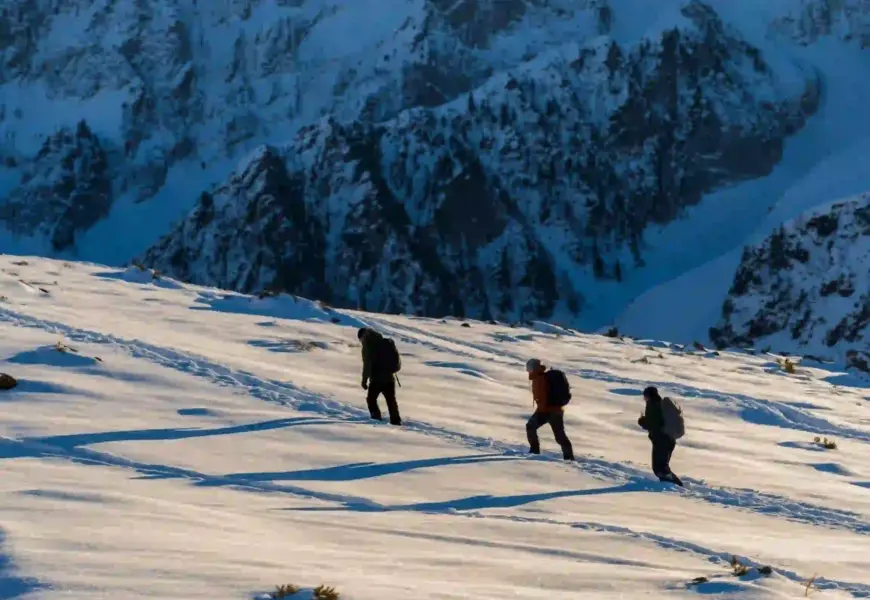 drei personen mache eine Wanderung durch den schnee