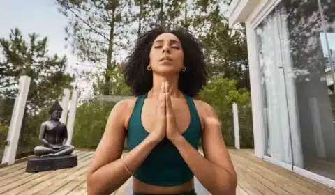 Frau hat die Augen geschlossen und macht in ihren Yogaklamotten die 4-7-8-Atmung.