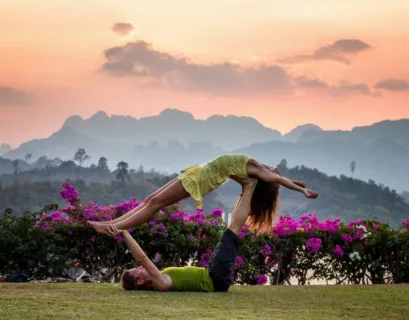 Mann und Frau beim Paar-Yoga mit Blumen im Hintergrund