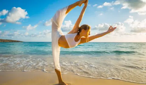 Frau macht yoga am Strand