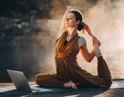 Frau macht Yoga vor ihrem Laptop