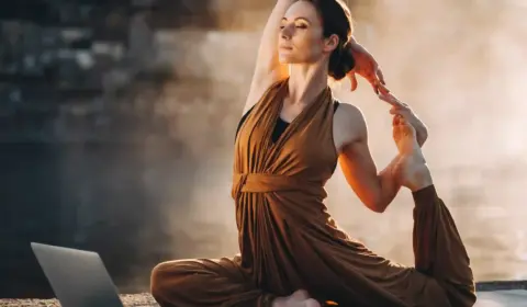 Frau macht Yoga vor ihrem Laptop