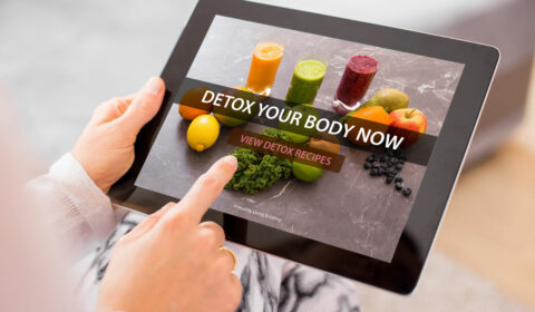 Frau hält Tablet mit dem Slogan „DETOX YOUR BODY NOW"