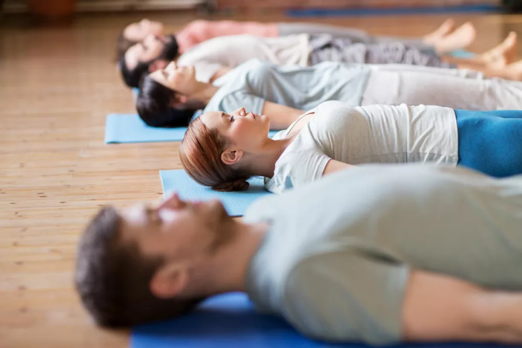 Gruppe von Menschen macht Yoga-Übungen bei Tinnitus im Studio