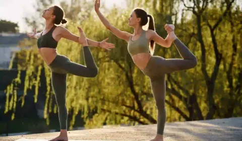 zwei-frauen-machen-Yoga-und-stehen-auf-einem-Bein