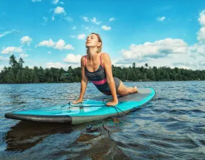 Fraucht macht die Yogaübung heraufschauender Hund auf dem SUP