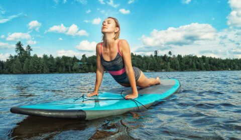 Fraucht macht die Yogaübung heraufschauender Hund auf dem SUP