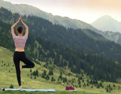 Frau macht Yoga im Freien mit Blick auf die Berge