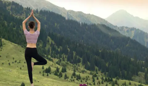Frau macht Yoga im Freien mit Blick auf die Berge