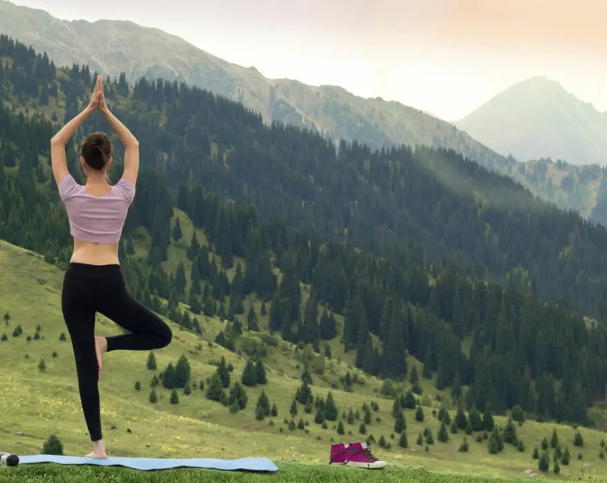 Frau macht Yoga im Freien mit Blick auf die Berge