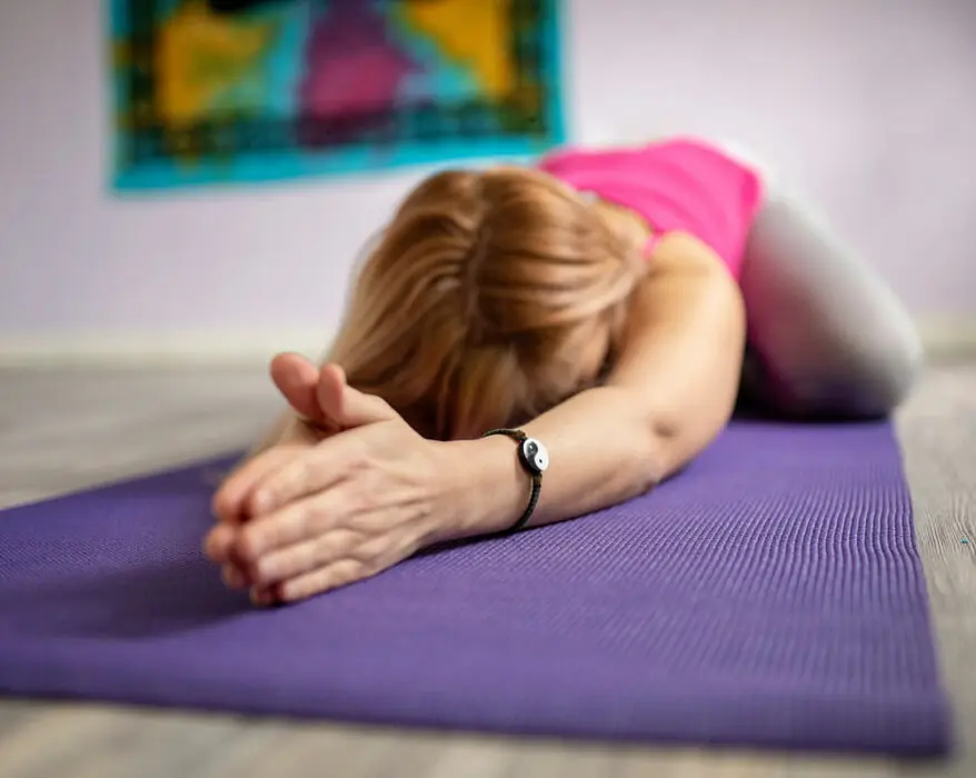Frau liegt auf der Yogamatte und macht Yin Yoga Übungen