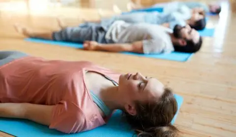 Gruppe liegt in der Yogastunde auf dem Boden und machen Shavasana