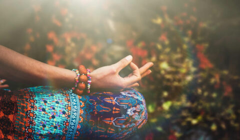 Frau sitzt im Meditationssitz und hält ihre Finger im Mudra
