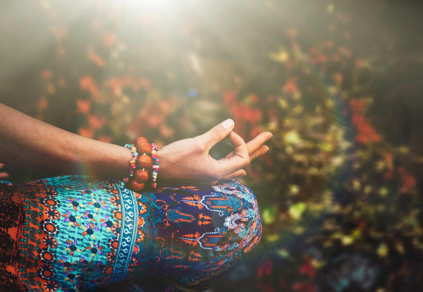 Frau sitzt im Meditationssitz und hält ihre Finger im Mudra