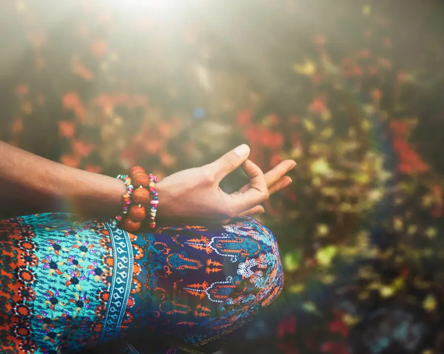 Frau sitzt im Meditationssitz und hält ihre Finger im Mudra