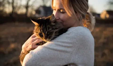 Frau kuschelt mit Katze auf dem Arm