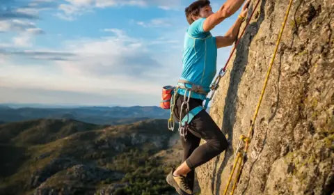 Mann klettert in Portugal an einer Felswand