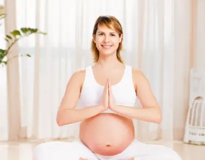 Schwangere Frau macht Yoga und schaut in die Kamera